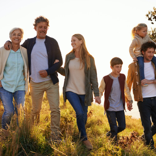 A happy family of six takes a morning walk through tall grass.