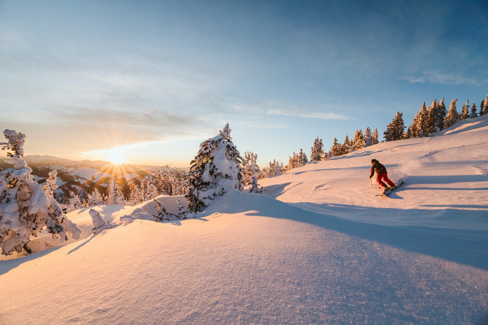 A backcountry skier takes fresh turns at sunset.