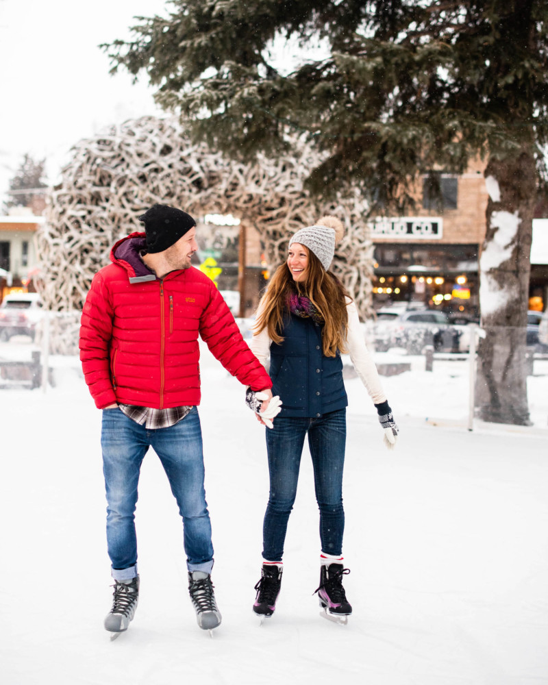A happy couple ice skates on the town square in Jackson Hole.