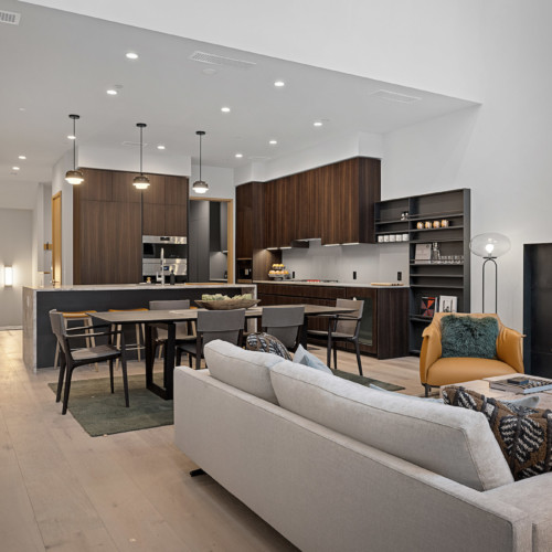 An elegant and modern condo interior with walnut kitchen cabinets, a white couch, and oak floors.